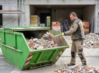 Container auf Baustelle wird mit Bauschutt befüllt